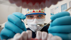 Dental professional examining teeth during a post-dental implant recovery consultation.
